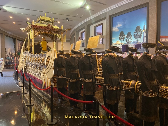 mannequins in black accompanying a royal chariot
